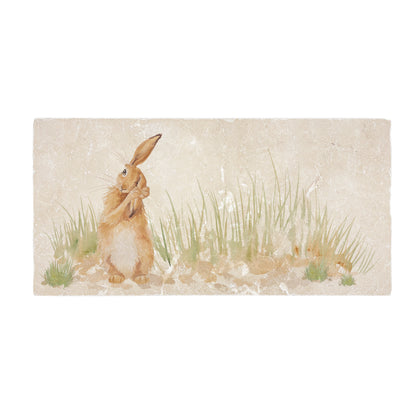 A handmade rectangle cream marble splashback tile featuring a watercolour countryside animal design of a hare in grass cleaning his ear.