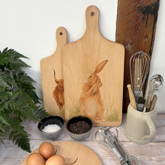 Handmade paddle board in Beech wood, featuring a painted Hare washing it ear with a hand tied luxury blue ribbon. 