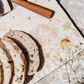 A medium square platter with a watercolour bumblebee design, the platter is being used to serve bread on an al fresco dining table.