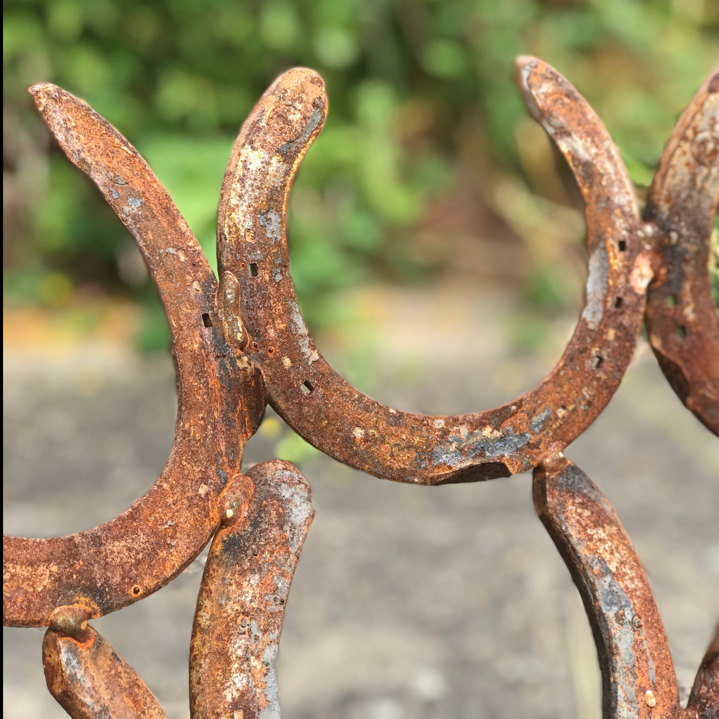 A closeup of horseshoes forming a handmade fire pit. The horseshoes have an authentic rust finish.
