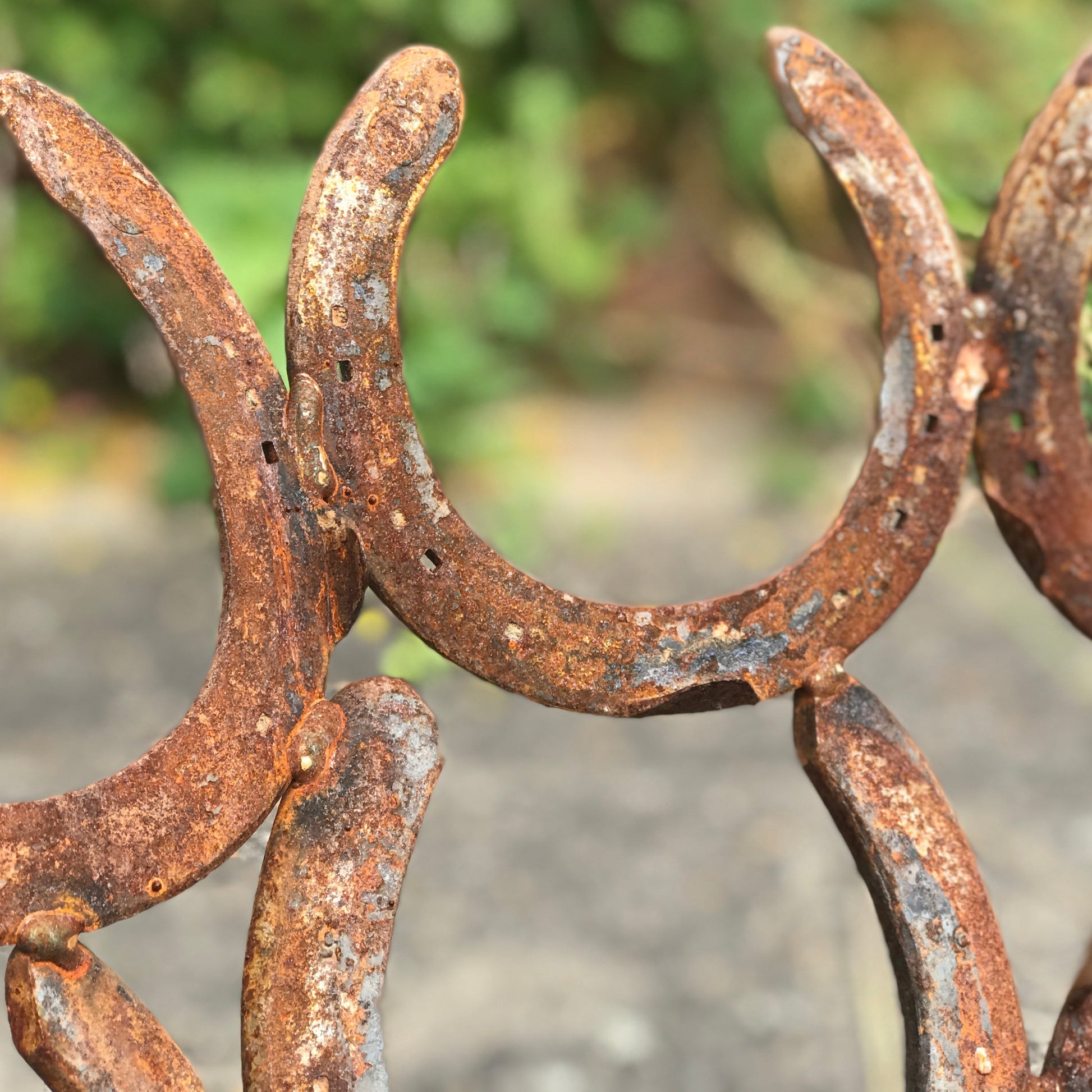 A closeup of horseshoes forming a handmade fire pit. The horseshoes have an authentic rust finish.