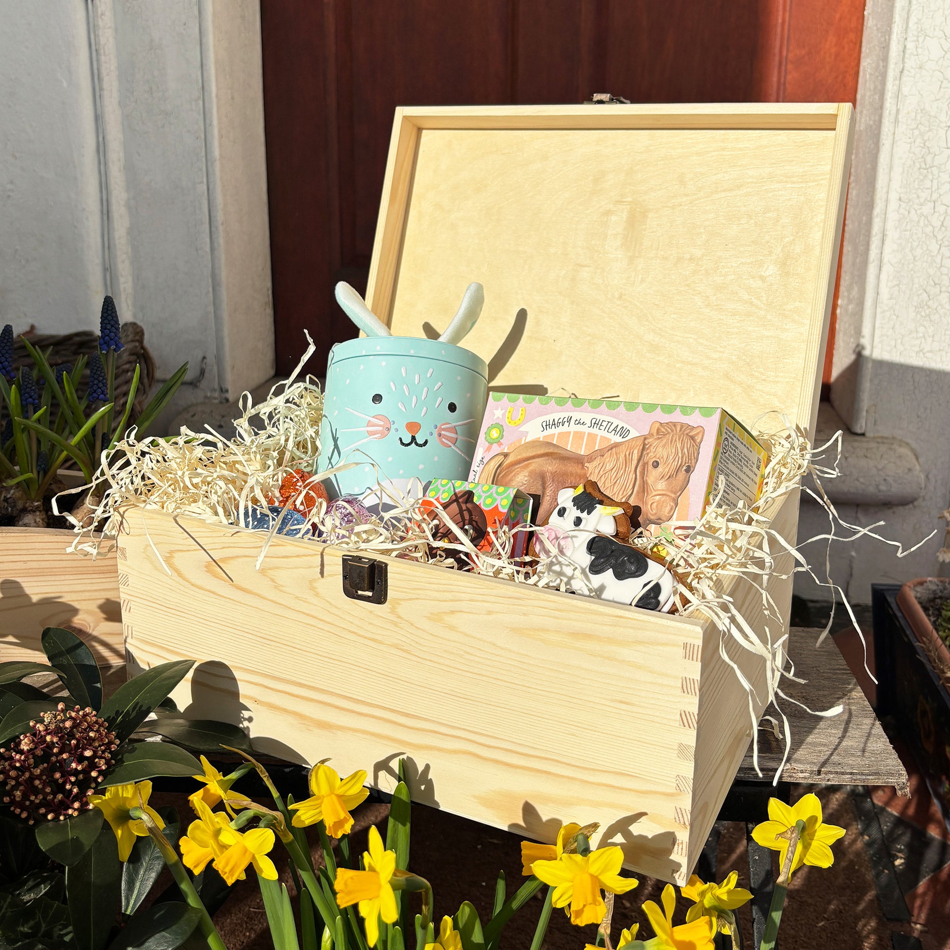 Large Easter personalised wooden pine box, perfect for Easter treats, eggs, gifting. Children gifts. This box has a beautiful easter theme with 4 bunnies surrounded by some spring flowers and some bees. This box can be personalised in 4 phrases or it can just have the design and no text. This Picture is to show an example of the Easter Bunny dropping off a special delivery full of easter treats.