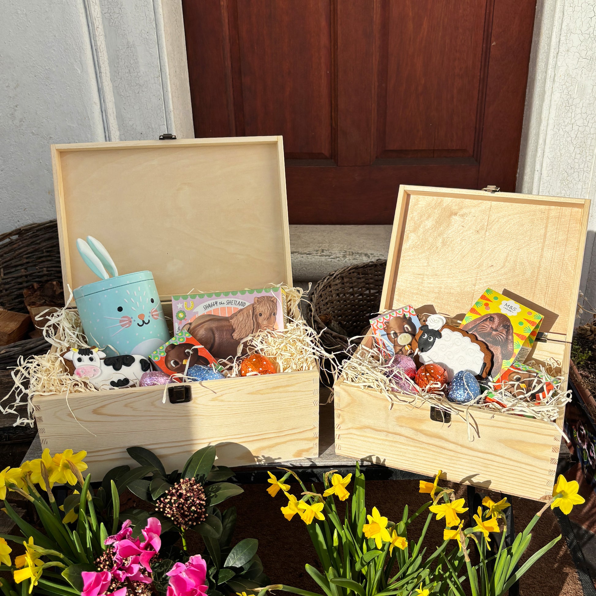 Large & Small Easter personalised wooden pine box which has an antique clasp perfect for Easter treats, eggs, gifting. Children gifts. This box has a beautiful easter theme with 6 lambs grazing in a spring meadow. This box can be personalised in 4 phrases or it can just have the design and no text. The Ester box is full with lots of chocolate easters eggs and biscuits perfect for gifting. This Box has been delivered by the easter bunny with an example of some easter boxes filled with treats. 