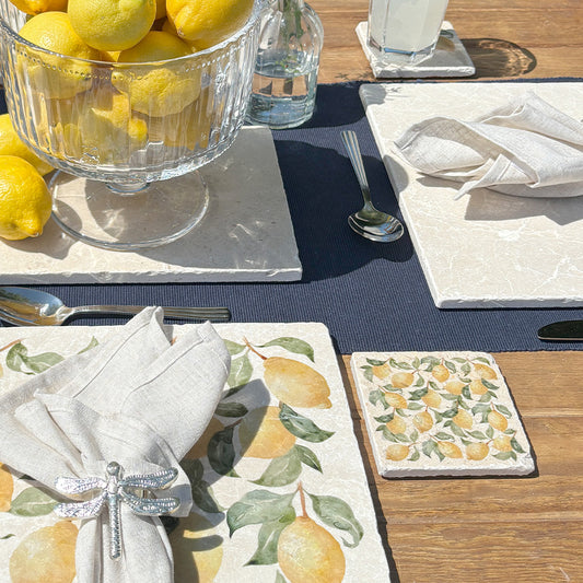 A garden table set with marble placemats and coasters featuring a maximalist lemon pattern.