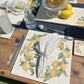 An al fresco dining table set with marble placemats and coasters featuring a minimalistic watercolour lemon design.