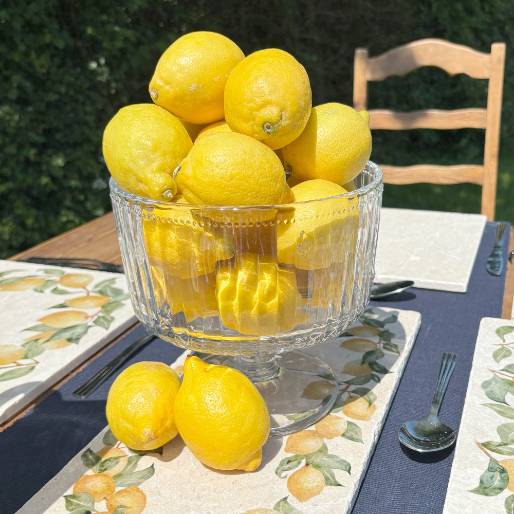 A garden table set with marble serving platters featuring a lemon wreath watercolour design.