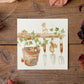 A square greetings card with a watercolour design of mice in a garden shed.