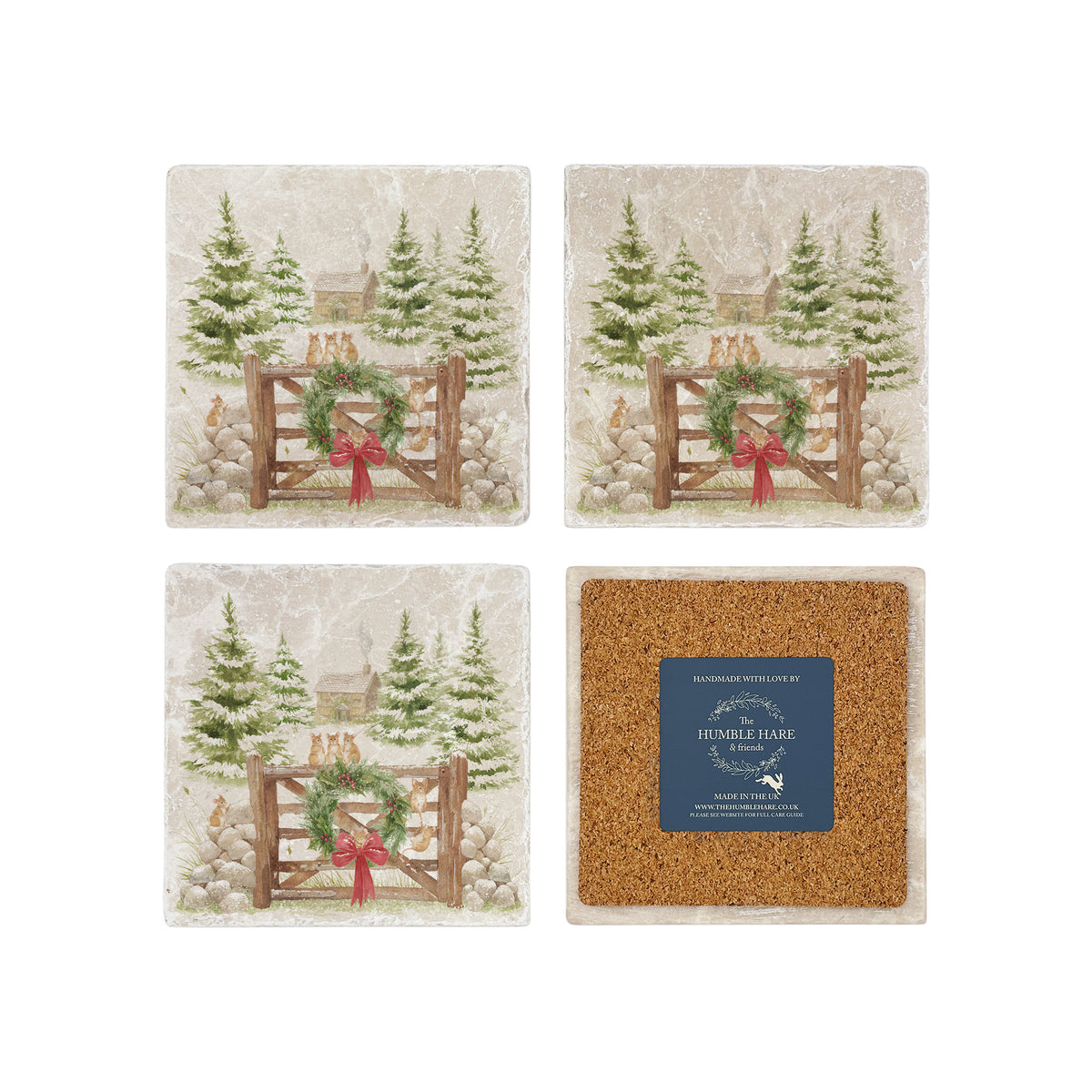 Set of four square coasters featuring a rustic Christmas scene with mice playing on a wooden gate, green wreath, red bow, snowy pine trees, and a small cottage. One coaster is flipped to show the back is covered with cork to protect surfaces.