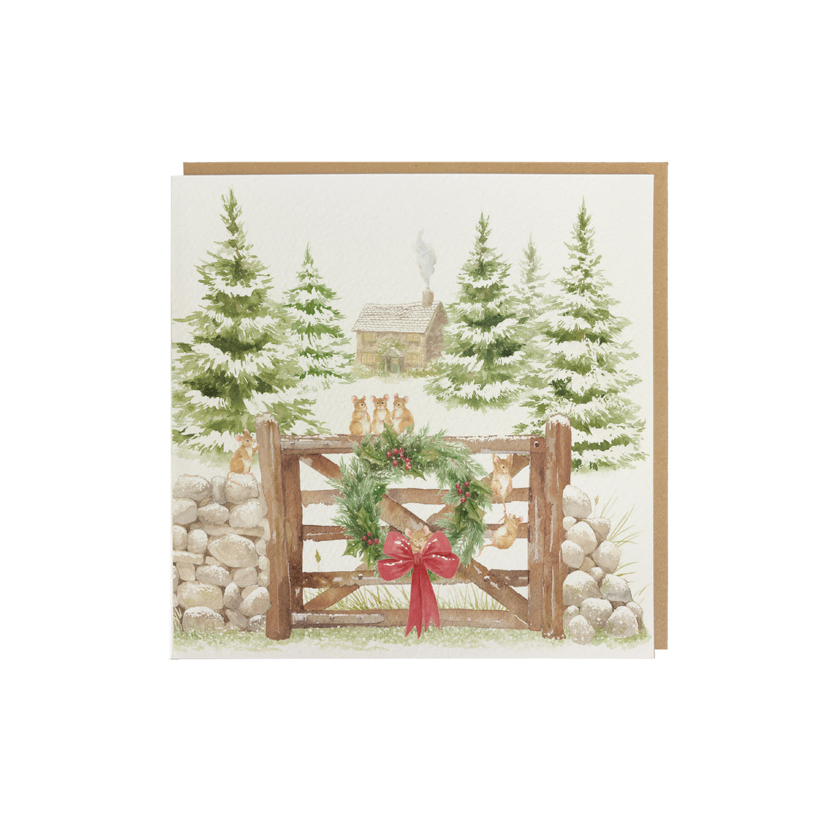 A square greeting card featuring a rustic winter landscape illustration with mice on a wooden fence, green wreath, red bow, evergreen trees, a stone wall, and a cabin in the background, shown on a white studio background.