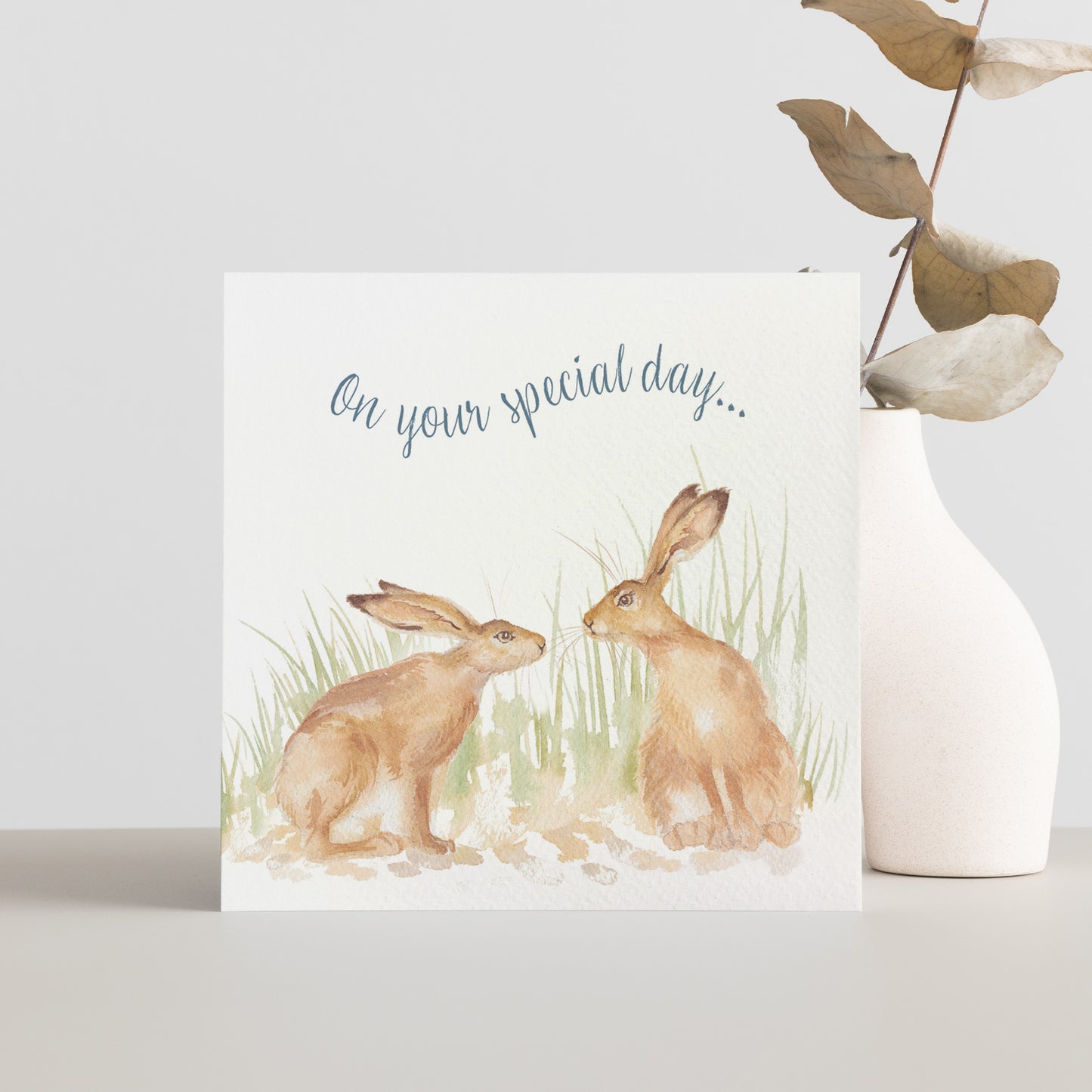 A greetings card reading On Your Special Day in dark blue text above a hare couple in a watercolour style.