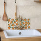 A rectangular marble splashback tile behind a country kitchen sink, the tile features a watercolour orange fruit pattern.