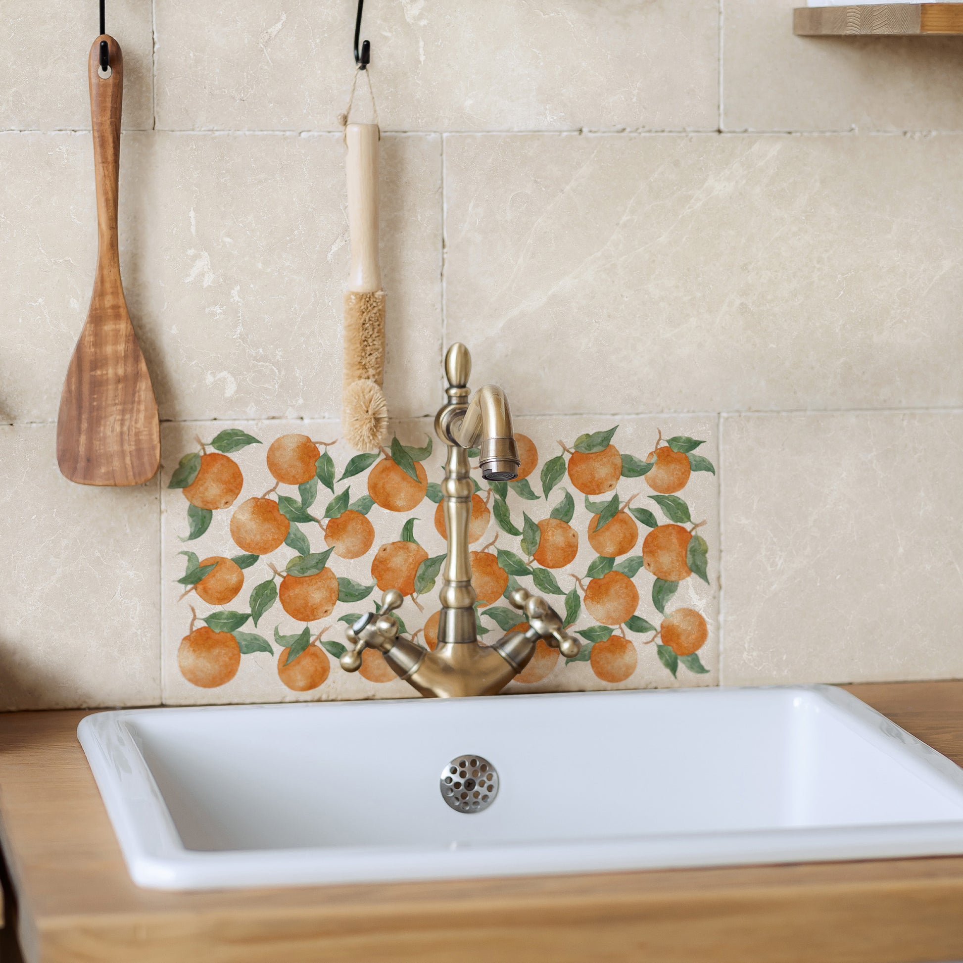 A rectangular marble splashback tile behind a country kitchen sink, the tile features a watercolour orange fruit pattern.