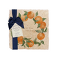 A personalised marble platter featuring a wreath of oranges and leaves, with a bespoke message in the centre of the design. The platter is packaged with a luxurious blue gift bow and tag.