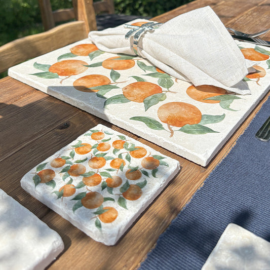 A garden table set with marble placemats and coasters featuring a maximalist orange pattern.