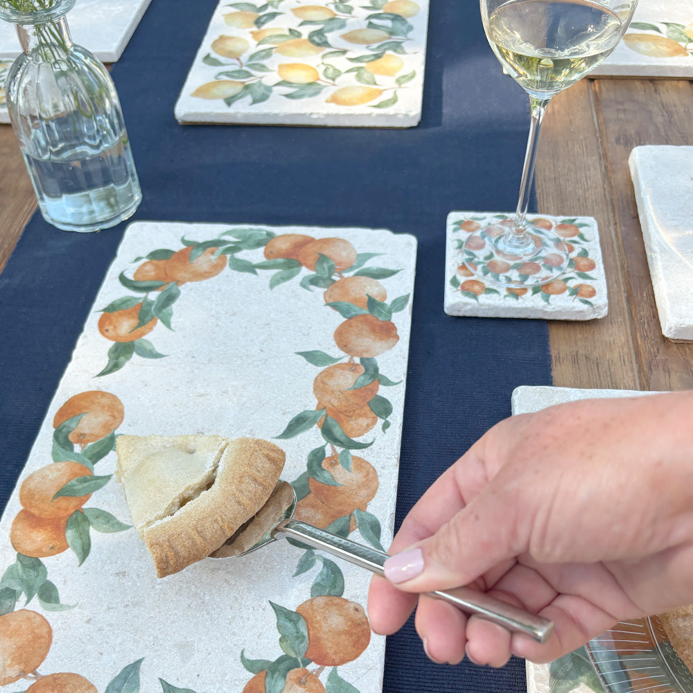 A table set with a collection of marble platters and coasters featuring Mediterranean oranges.