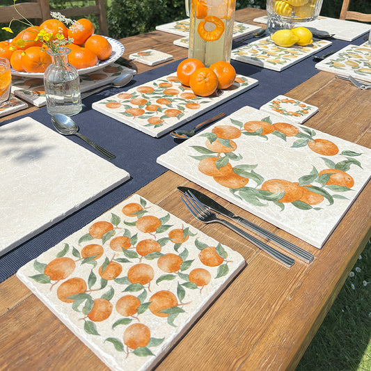 A square medium multipurpose platter used as a side plate on an outdoor dining table. The platter features a maximalist pattern of oranges and green leaves.