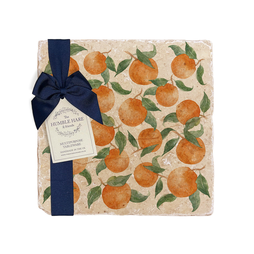 A medium multipurpose marble platter with a watercolour oranges and leaves pattern, packaged with a luxurious dark blue bow and branded gift tag.