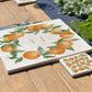 A personalised marble placemat with a orange and leaves wreath design, with a custom personalised message in the centre. The placemat is set on a garden table in the sunshine.