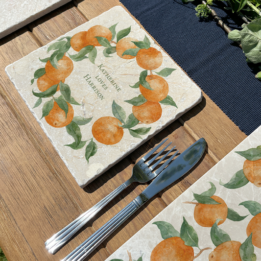 A medium marble serving board personalised with the bespoke message 'Katherine Loves Harrison'. The serving board is set on a table in a sunny garden.