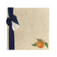 A large multipurpose marble platter with a watercolour orange design, packaged with a luxurious dark blue bow and branded gift tag.