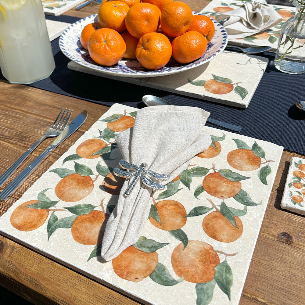 A garden table set with marble placemats and serving platters featuring watercolour Mediterranean oranges designs.