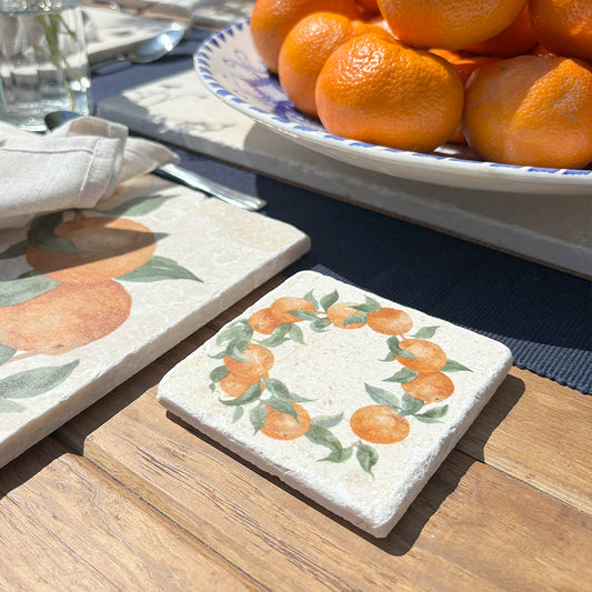 A square marble coaster featuring a watercolour wreath of oranges and green leaves.