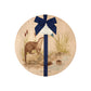 Round beech wood chopping board featuring a watercolour design of otters and a kingfisher down by the river bank. The wooden board is finished with a blue gift ribbon and tag.