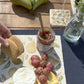 A garden table set with a marble cheeseboard and coaster featuring a maximalist pear pattern.