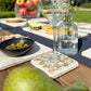 A garden table set with marble placemats and coasters featuring a maximalist pattern of golden green pears.