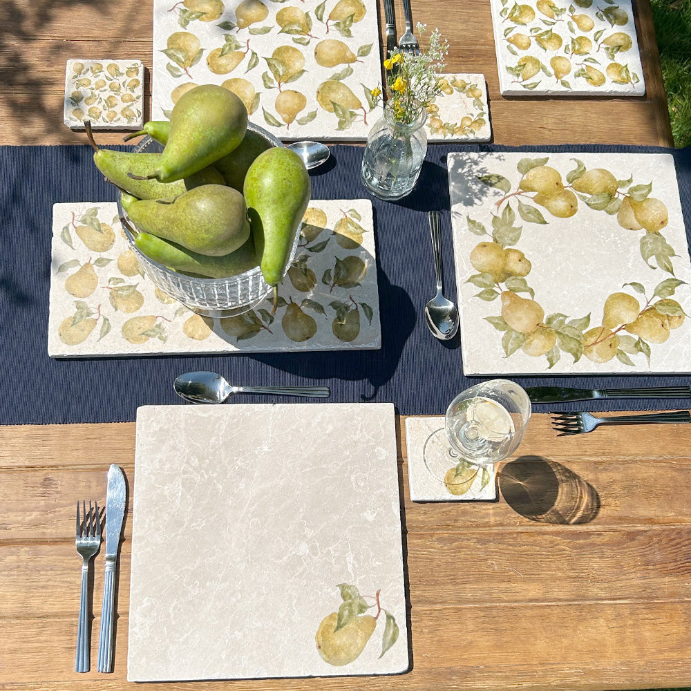 A garden tablescape set with handmade marble platters and coasters ready for a dinner party. The platters feature an elegant golden pear pattern.