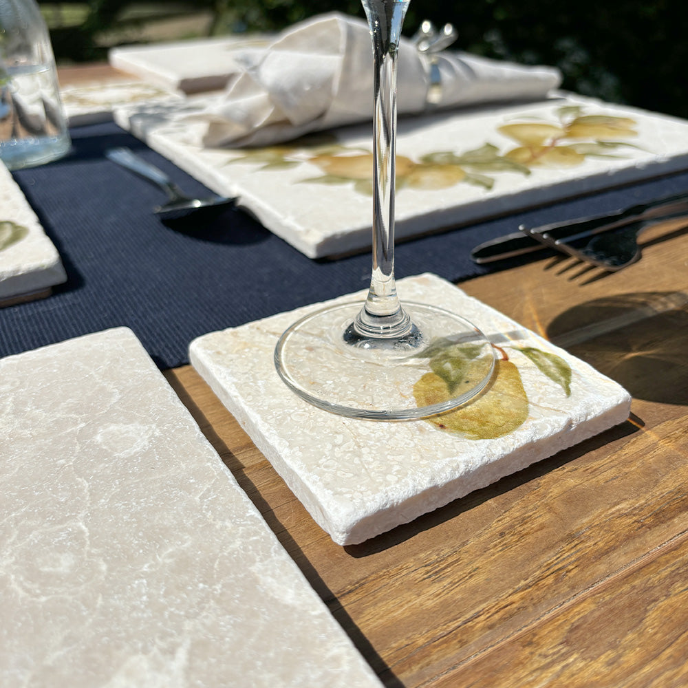 A square marble coaster on a garden table featuring a minimalistic watercolour pear design.