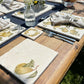 A table laid for an elegant dinner party in the garden, set with marble placemats and coasters that feature a watercolour pear design.