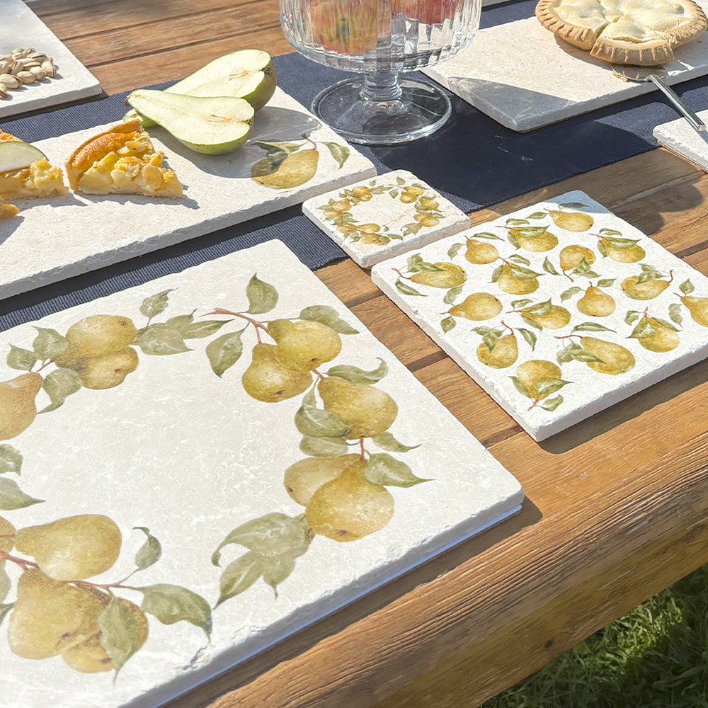 An al fresco dining table set with handmade marble coasters and placemats featuring a watercolour pear wreath design.