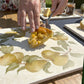 A large marble platter featuring a watercolour pear wreath design. The platter is being used as a serving board for an apple, pear and frangipane tart.