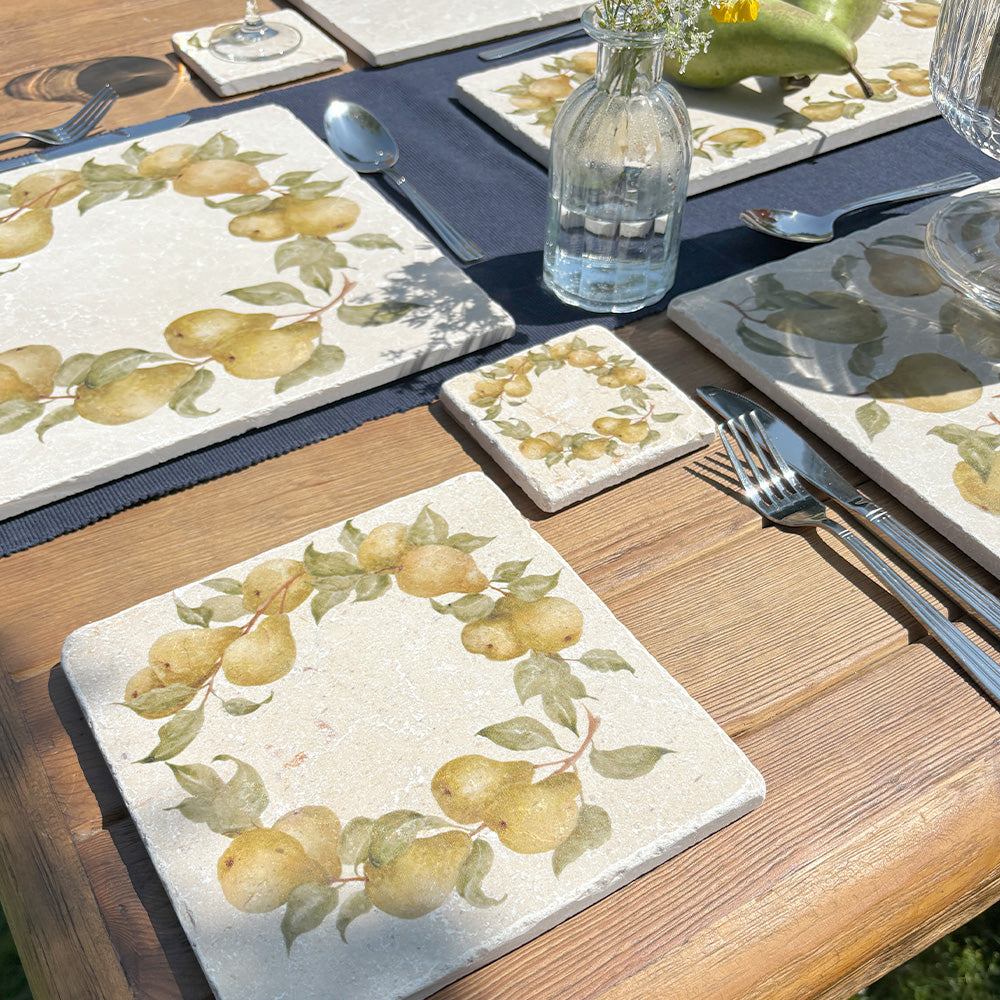 A medium square marble platter featuring a watercolour pear wreath design. The platter is set on a dinner table next to a marble placemat and coaster.