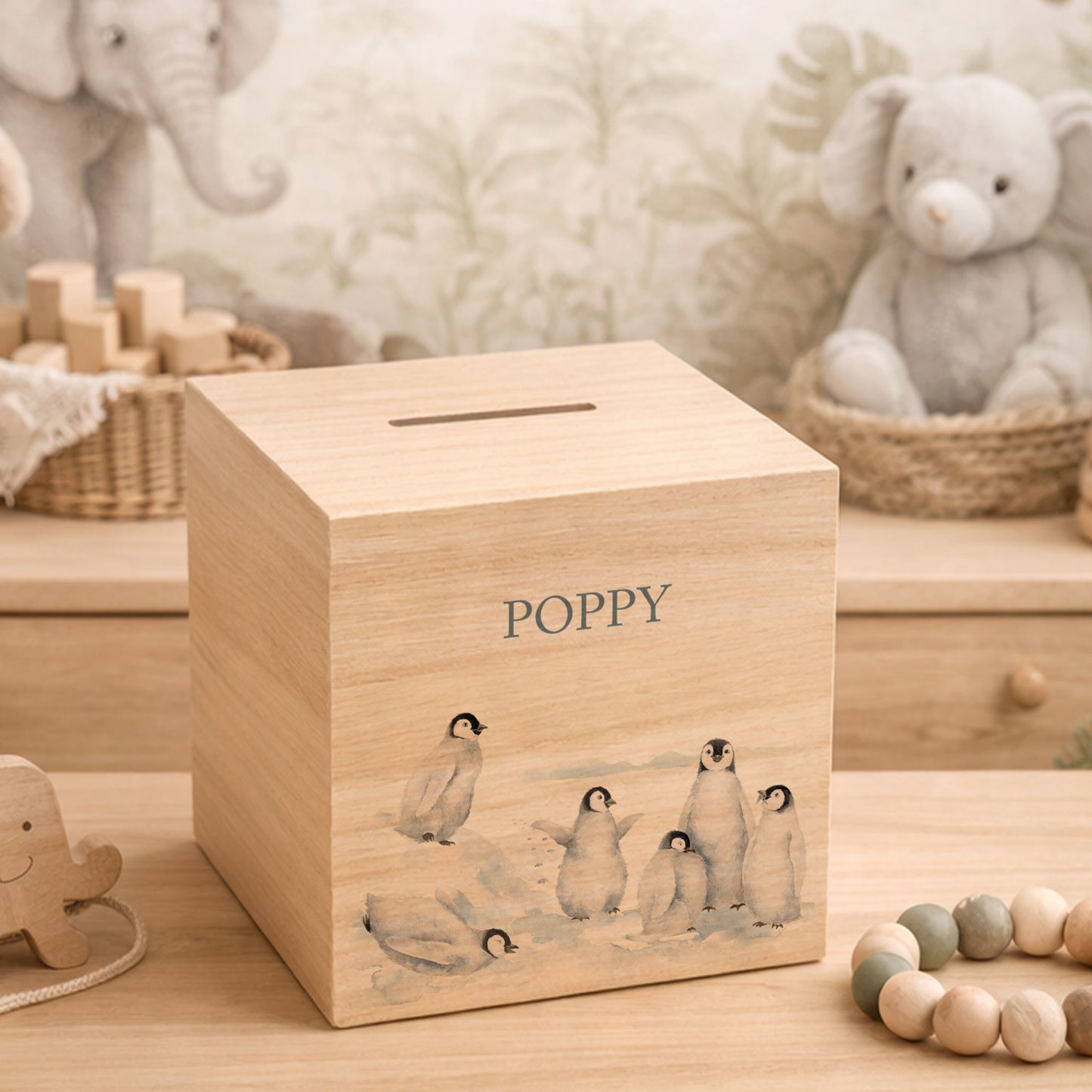 handmade nursery keepsake money box with delicate watercolour design, a group of Penguins playing, slipping and sliding in the snow. 