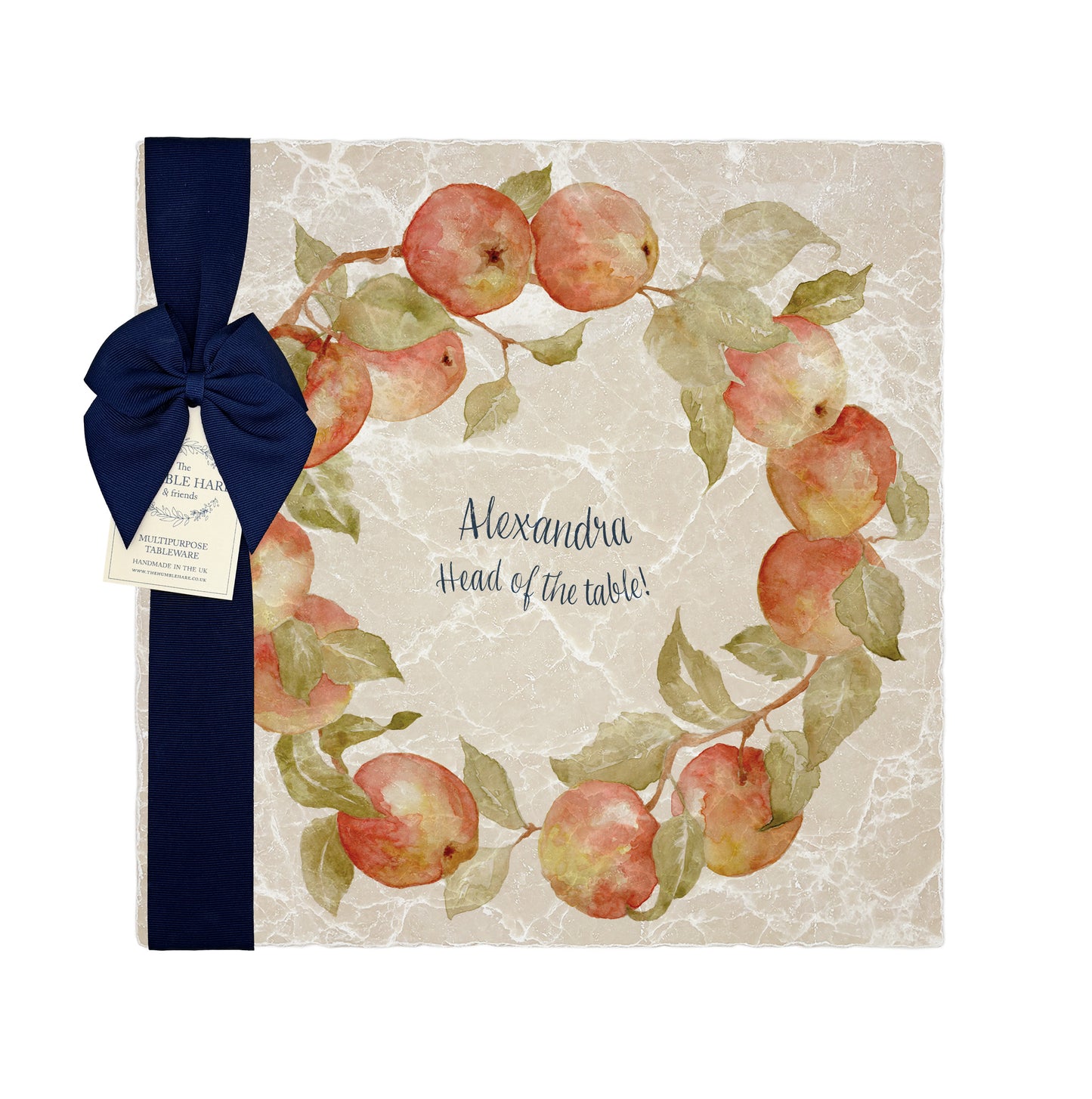 A large square personalised marble placemat with an apple wreath design. The Placemat is packaged with a luxurious dark blue bow and The Humble Hare branded gift tag.