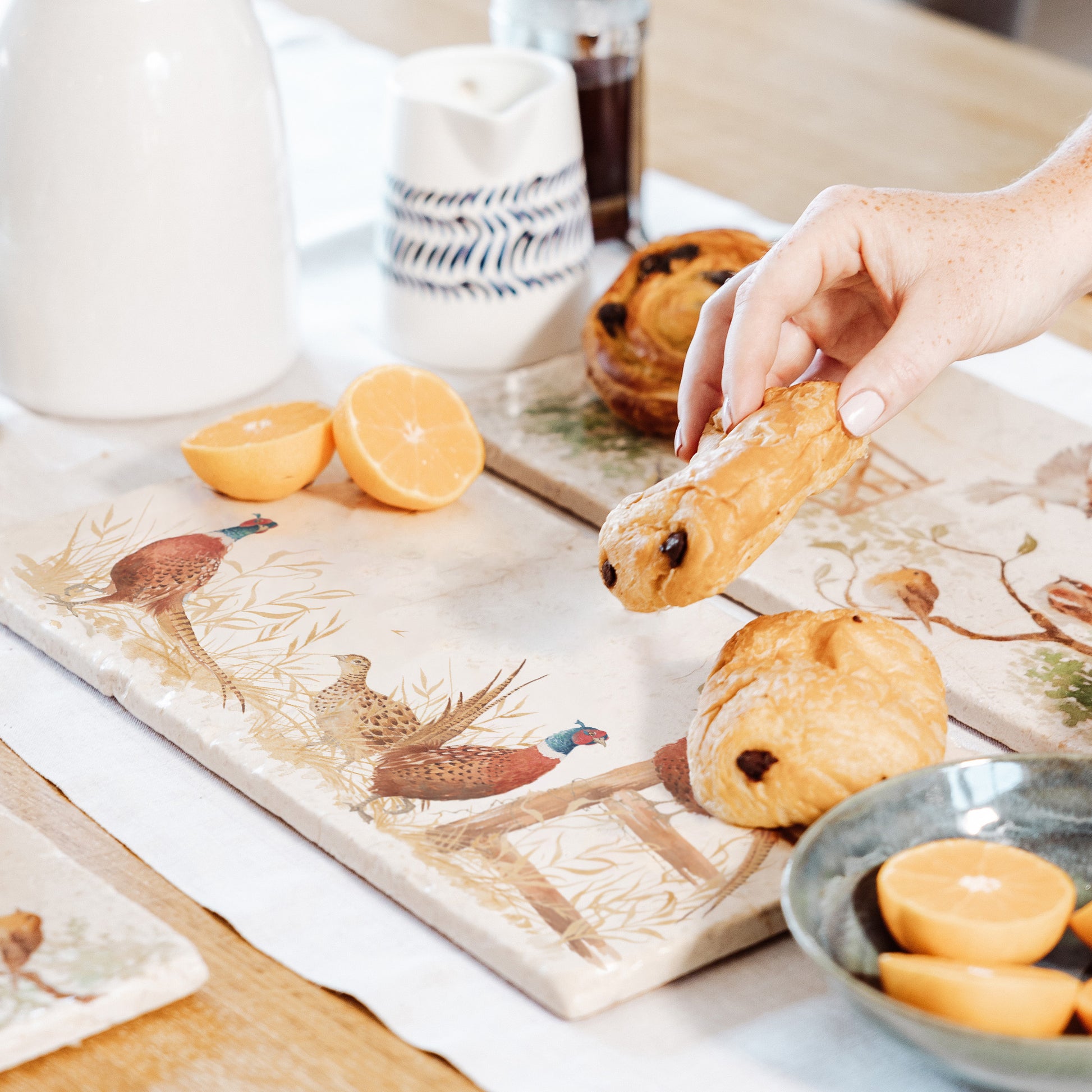 A rectangular marble serving platter, featuring a watercolour design of four pheasants around a countryside fence post in golden grass.