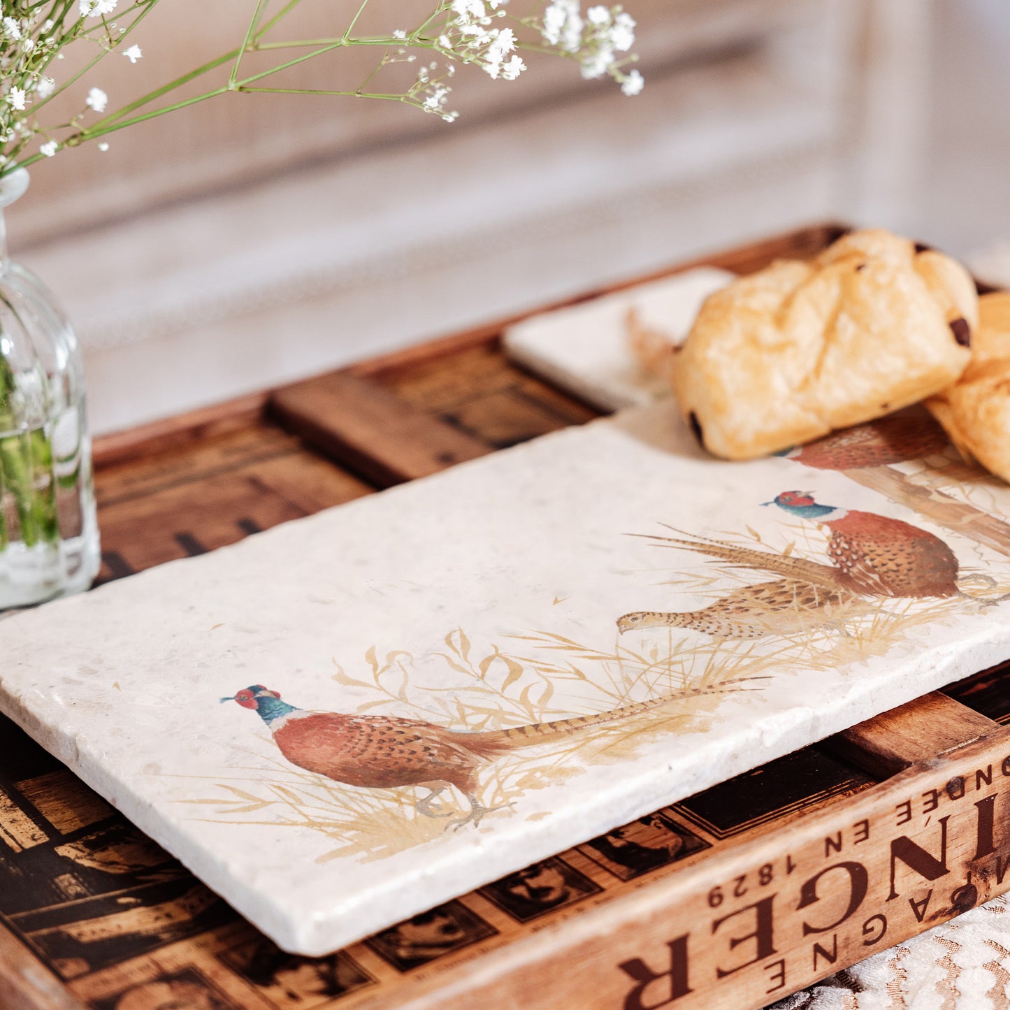 A rectangular cream marble sharing platter, featuring a watercolour design of four pheasants around a countryside fence post in golden grass.