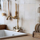 A tiled splashback behind a sink in a country kitchen. The splashback is made up of medium plain cream marble tiles.