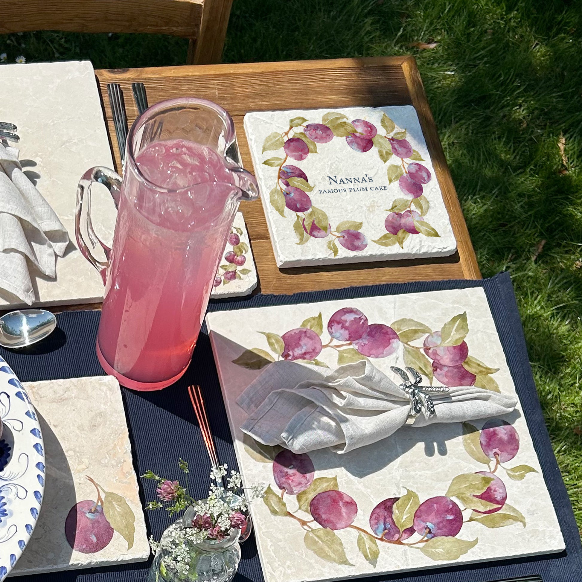 A medium personalised square marble platter featuring a watercolour plum wreath design. The platter is being used to serve a plum tart.