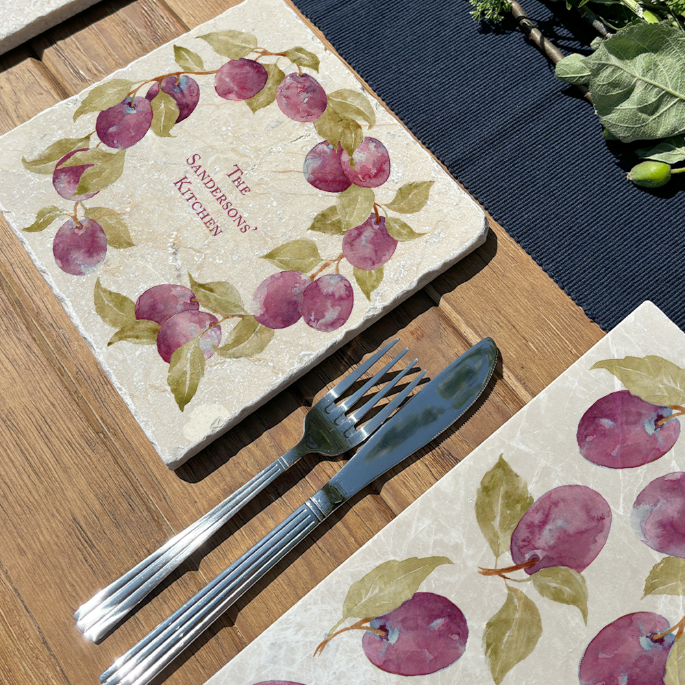 A medium marble cheese board personalised with a bespoke family name. The serving board is set on a table in a sunny garden.