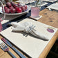 A sophisticated outdoor dining table set with marble placemats and coasters featuring a minimalistic plum design.