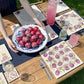 A garden table set with marble placemats and serving platters featuring a plum watercolour design.