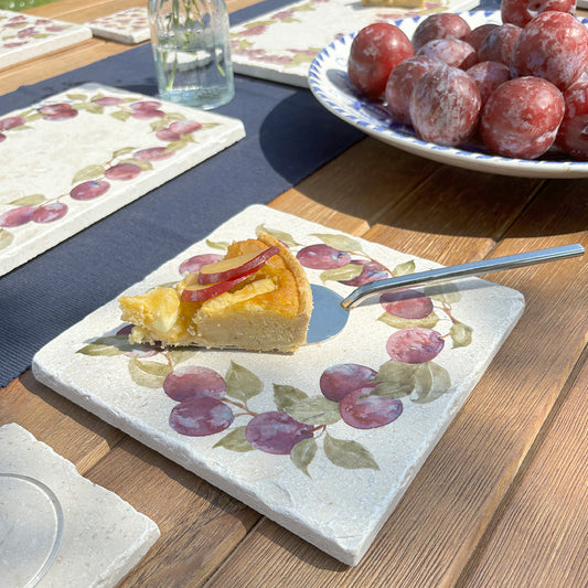 A medium square marble platter featuring a watercolour plum wreath design. The platter is being used to serve a plum tart.