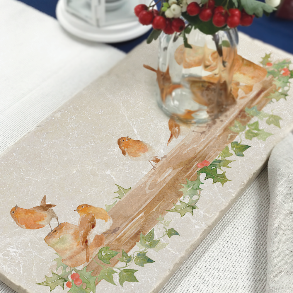 A rectangle marble sharing platter set on a dinner table as a centrepiece. The platter features a Christmas design with robins and holly.