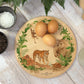 Round wooden chopping board on a kitchen worktop. The beech wood board features a watercolour design of rainforest animals in the jungle.