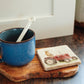 A square marble coaster with a golden retriever dog sat on a vintage red tractor. The coaster is on a kitchen work surface.