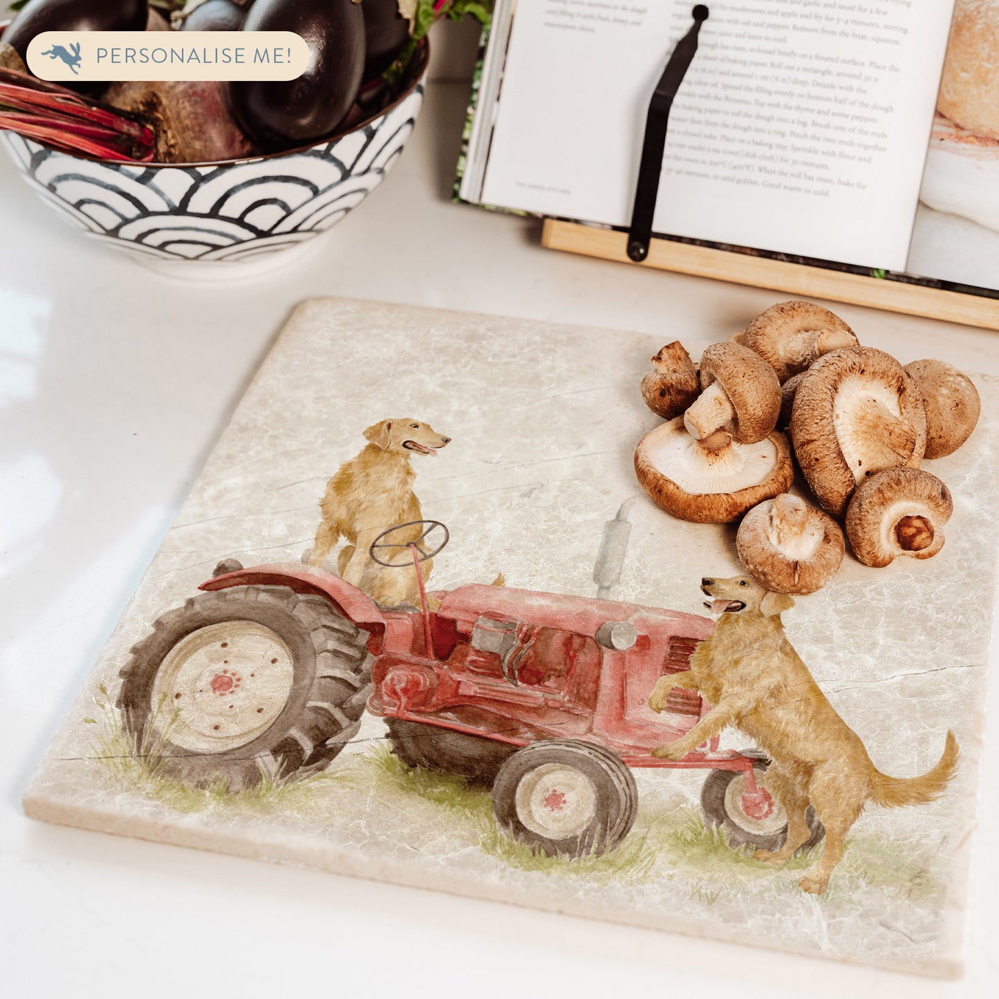 A square large marble platter with golden retriever dogs sat on a vintage red tractor. The marble platter is sat on a farmhouse kitchen worktop.