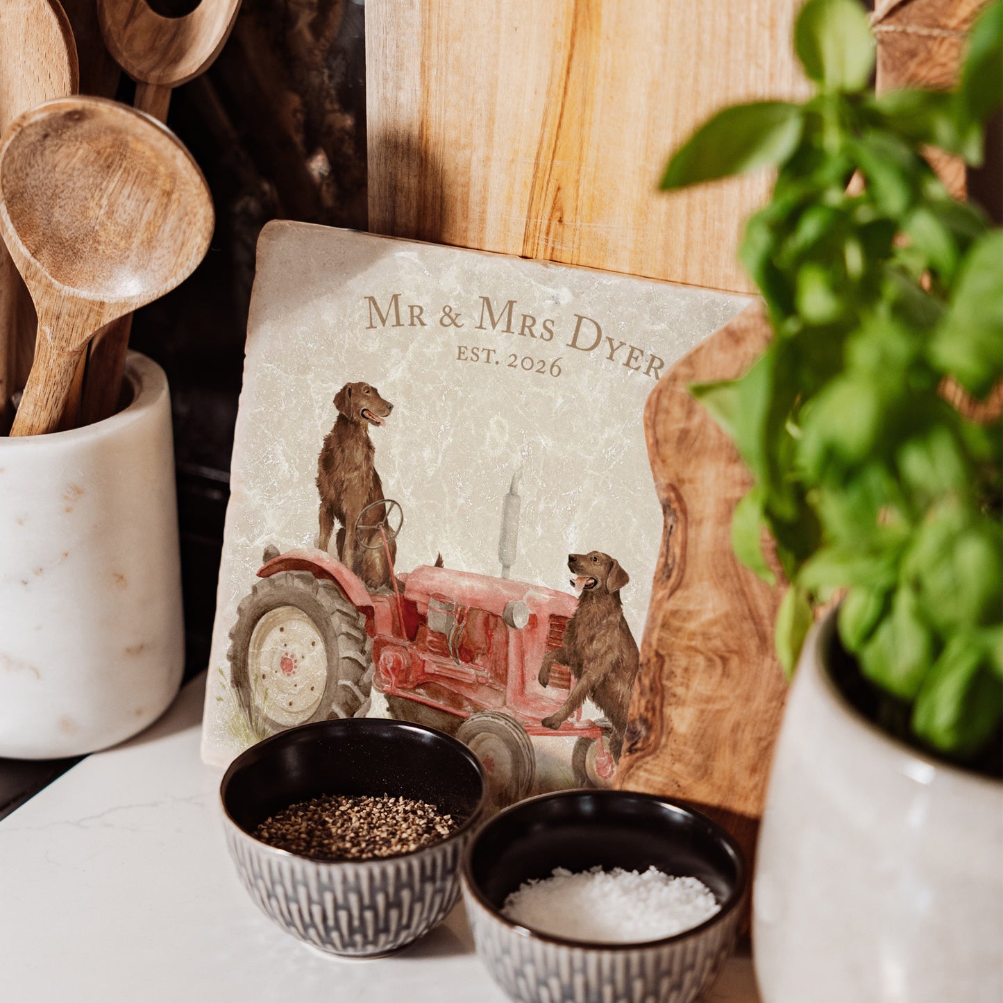 A square medium marble platter with chocolate Labrador retriever dogs sat on a vintage red tractor. The marble platter is sat on a farmhouse kitchen worktop.